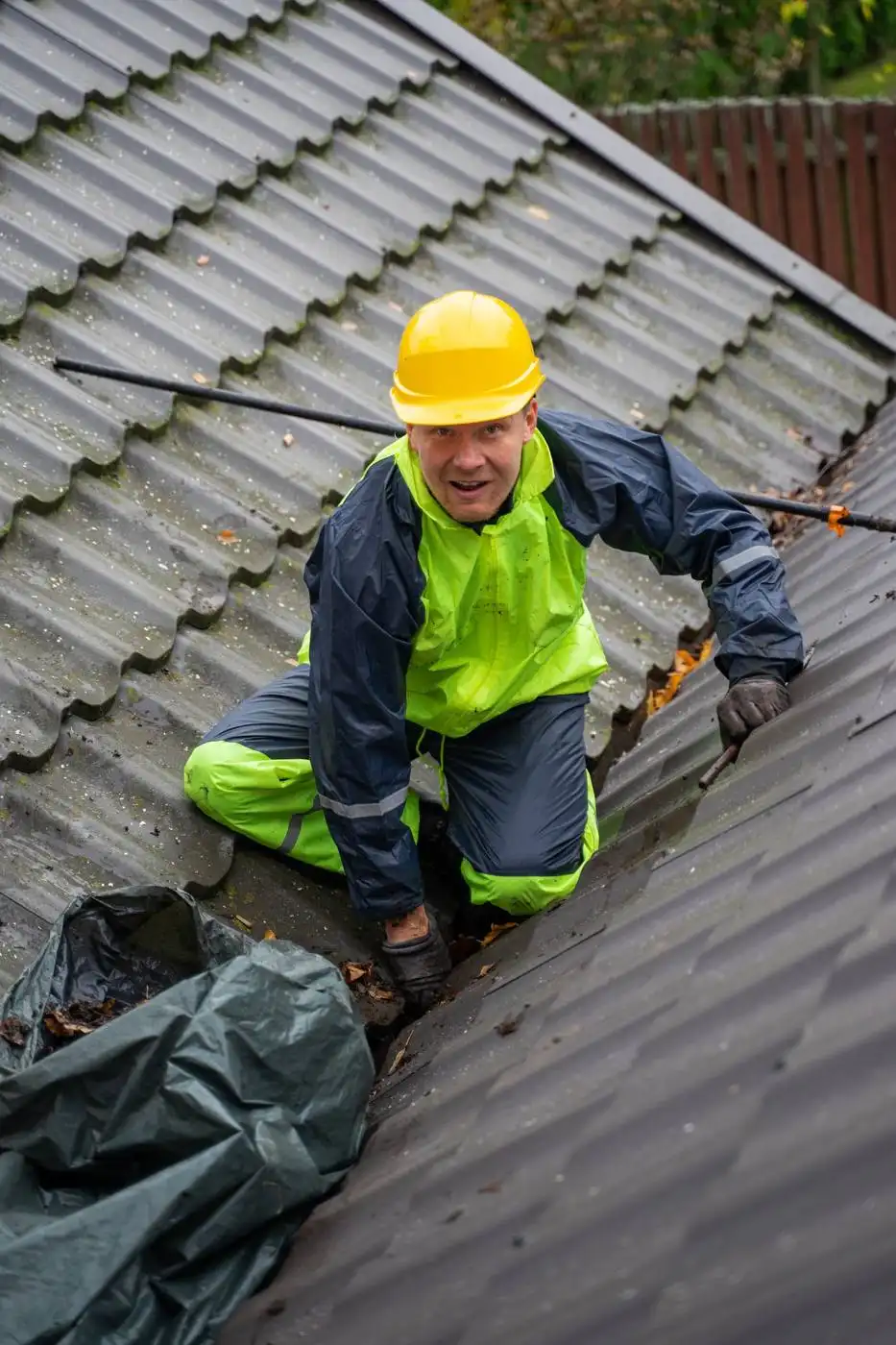 Dachdecker mit Helm arbeitet auf einem Ziegeldach