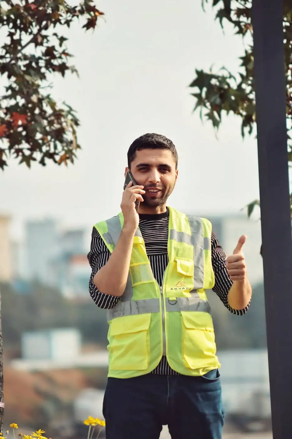 Handwerker in Warnweste telefoniert auf einer Baustelle